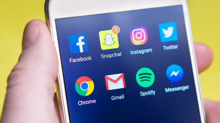 A person demonstrating marketing strategy with a cell phone displaying branded social media icons.